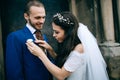 The bride touches the boutonniere groom. Happy romantic young couple celebrating their marriage in church