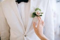 The bride touches the groom`s boutonniere on a white jacket Royalty Free Stock Photo