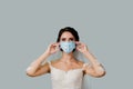 Bride touches her medical mask at coronavirus covid-19 quarantine period. Girl in wedding dress on white background with Royalty Free Stock Photo