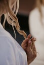 Bride touching her beautiful curl hair with fingers. Preparation of the blonde bride. Close up. Women doing hairstyle herself.