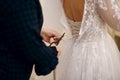 The bride tries on a wedding dress before buying, the seamstress cuts the long ribbons with scissors