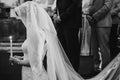 Bride under veil praying with candle light. Happy stylish wedding couple holding candles during holy matrimony in church. Royalty Free Stock Photo