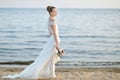 Bride walking along sea coast on sunset