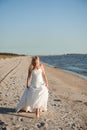 Bride walking along sea coast wearing beautiful wedding dress. Royalty Free Stock Photo