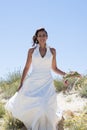 Bride walking along sea coast wearing beautiful wedding dress Royalty Free Stock Photo