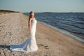 Bride walking along sea coast wearing beautiful wedding dress Royalty Free Stock Photo