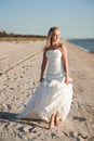 Bride walking along sea coast wearing beautiful wedding dress. Royalty Free Stock Photo