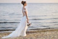 Bride walking along sea coast in wedding dress