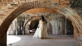 Bride Walking Under Brick Arches