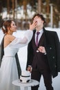 The bride wants to smear the groom`s face with a piece of wedding cake. Shooting in the winter forest