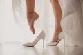 Bride wearing high heel shoe on mirror floor near panoramic window on wedding day. Bride putting her elegant leg into white shoe Royalty Free Stock Photo