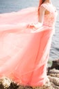 The bride is wearing a wedding dress gently coral color on the sea. Beautiful tulle. The concept of fashion colors 2019 Royalty Free Stock Photo