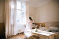 The bride wears a wedding dress in bedroom. Last preparations for the wedding. Wedding morning