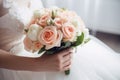 A bride in a white lace wedding dress holding a bouquet of white and delicate pink roses Royalty Free Stock Photo