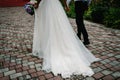 The bride with wedding bouquet and groom goes back on the pavement and hold hands on a stroll along the street in the city. Bottom Royalty Free Stock Photo