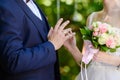 The bride with a wedding bouquet put a gold wedding ring on the groom& x27;s finger. Wedding ceremony, exchange of rings. Royalty Free Stock Photo