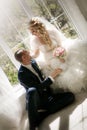 Bride with a wedding bouquet from roses and the groom sitting at a window Royalty Free Stock Photo