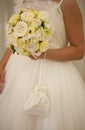 Bride with wedding bouquet of white and yellow roses, silk bag with pearls ang strings