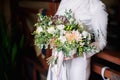 Bride on the wedding day holds in her hands a stylish modern wedding bouquet of succulents, carnations and hydrangeas Royalty Free Stock Photo