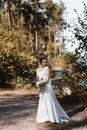 Bride in the wedding drees standing in the forest with her head titled to the shoulder Royalty Free Stock Photo