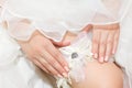 Bride in wedding dress adjusts her garter.