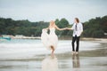 Bride in wedding dress and groom walking on the sea. Wedding on a deserted beach. Royalty Free Stock Photo
