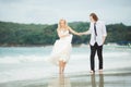 Bride in wedding dress and groom walking on the sea. Wedding on a deserted beach. Royalty Free Stock Photo