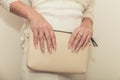 The bride in a wedding dress holds in hand a white bag. Beautiful manicure. Wedding day. Wedding rings. Royalty Free Stock Photo