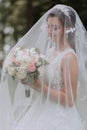 the bride in a wedding dress with a long train and a veil holds a wedding bouquet Royalty Free Stock Photo