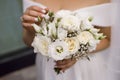 The bride in a wedding dress and a long veil holds a white wedding bouquet of roses Royalty Free Stock Photo