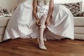 Bride in wedding dress putting on stockings silk garter, wedding Royalty Free Stock Photo