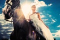Bride in wedding dress riding a horse, backlit Royalty Free Stock Photo
