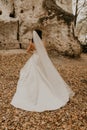 bride in wedding dress run away through autumn forest on fallen orange leaves to mountain Royalty Free Stock Photo