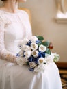 The bride in a wedding dress sits and holds in her hands a delicate bouquet with white and blue flowers Royalty Free Stock Photo