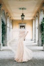 Bride in a wedding dress stands covered herself with a veil on an old pillared terrace. Lake Como