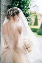 Bride in a wedding dress with a veil and a bouquet of flowers stands with her head turned near the wall. Lake Como. Back Royalty Free Stock Photo