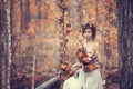 The bride on a wedding walk on a decorative swing, golden autumn