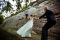 Bride whirls to a groom along a path behind an old stone wall Royalty Free Stock Photo