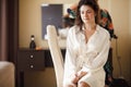 The bride in white bathrobe with her hair done at morning. Wedding preparations.