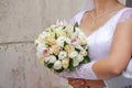 The bride in a white dress against a wall with a wedding bouquet, the groom embraces him from behind. hands of a man Royalty Free Stock Photo