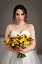 Bride in white dress with bouquet in photostudio