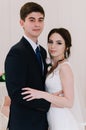 The bride in a white dress and groom in a blue suit are standing in the room and holding a wedding bouquet. Close-up portrait. Hap Royalty Free Stock Photo