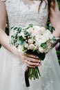 The bride in white dress are holding a beautiful wedding bouquet of pastel, pink, white peonies, roses flowers, greenery and Royalty Free Stock Photo