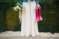 Bride in white dress with bouquet of flowers and pair of purple rubber boots