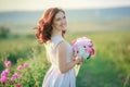 A bride in a white dress holds a bouquet of roses and callas on the background of green grass. Royalty Free Stock Photo