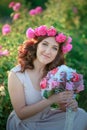 A bride in a white dress holds a bouquet of roses and callas on the background of green grass. Royalty Free Stock Photo