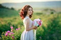 A bride in a white dress holds a bouquet of roses and callas on the background of green grass. Royalty Free Stock Photo