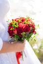 The bride in a white dress holds in her hands a stylish wedding bouquet of red roses. Wedding details Royalty Free Stock Photo