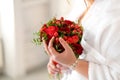 The bride in a white dress holds in her hands a stylish wedding bouquet of red roses. Wedding details Royalty Free Stock Photo