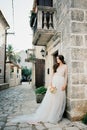 Bride in a white dress leaned against the stone facade of an old house Royalty Free Stock Photo